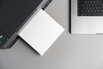 Printer and laptop on grey table in office