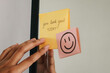 © Gatot - Woman putting a sticky note with phrase You Look Great Today! on the mirror.