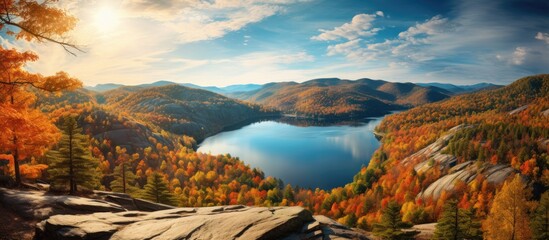 Wall Mural - In the grand landscape of nature, the majestic mountains stand tall, covered in lush green trees and vibrant autumn leaves. The sky's beauty reflects in the shimmering water, while the summer light
