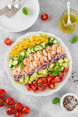 Wall Mural - Shrimp salad with vegetables and olive oil mustard dressing. Fresh seafood salad on a white plate on a gray concrete background. Healthy food. Copy space.