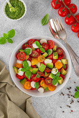 Wall Mural - Caprese salad with cherry tomatoes, mini mozzarella balls, avocado, pesto sauce and fresh basil. Healthy vegetarian meal.