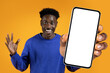 black guy offering huge smartphone with blank screen, orange backdrop