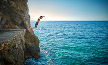 Boy Jumping From Cliff In Sea
