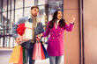 © Prostock-studio - Exhausted man reluctantly following excited shopaholic wife carrying bags outside