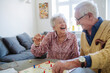 © Westend61 - Cheerful woman playing ludo with man at table in living room