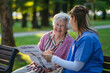 © Westend61 - Happy senior woman with healthcare worker holding newspaper in park