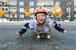 © Westend61 - Happy elementary girl lying on skateboard