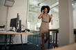 © Westend61 - Happy businesswoman talking on smart phone standing near door at office
