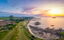 UK, Scotland, North Berwick, Aerial View Of Beach In Front Of Coastal Town At Sunset