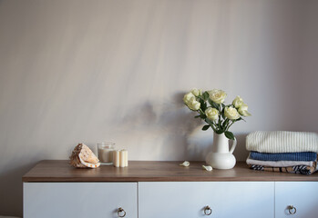 Sticker - knitted clothing and white roses in jug on modern dresser