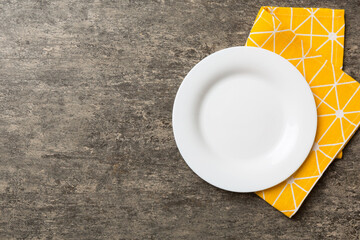 Wall Mural - Top view on colored background empty round white plate on tablecloth for food. Empty dish on napkin with space for your design