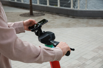 Wall Mural - Man using smartphone to pay and unblock electric kick scooter outdoors, closeup. Space for text