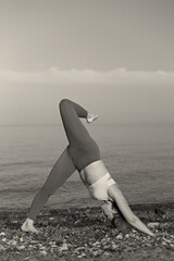 Sticker - Young woman performing down facing dog yoga pose on the beach