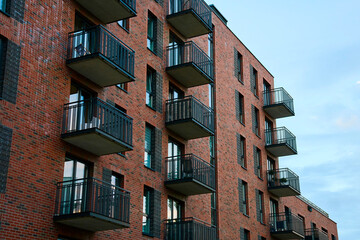 Wall Mural - Residential building facade with balconies and windows. Modern city architecture. Apartment building made of red bricks