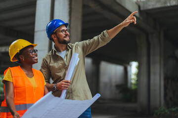 Young man architect explaining blueprint to supervisor wearing safety vest at construction site. Mid adult contractor holding blueprint and understanding manager vision at construction site.