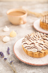 Wall Mural - Two tartlets with meringue cream and cup of coffee on brown concrete, side view, selective focus.