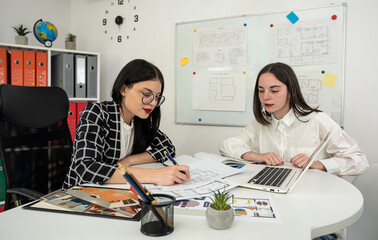 Wall Mural - Two young caucasian woman architects are working together to edit the draft house plan at office