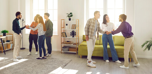 Wall Mural - Diverse group of cheerful smiling people friends or coworkers meeting in the living room together, talking and sharing news and stories with each other gathering at party at home. Banner.