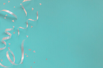 Wall Mural - close up on group of silver color of rolling ribbon and confetti on teal background with copy space 