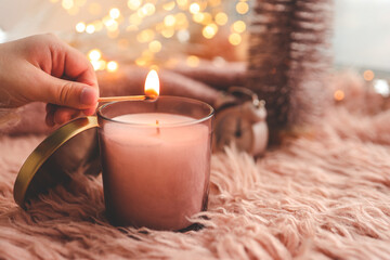 Wall Mural - A match lights a candle close-up, Christmas mood in pink colors