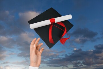 Canvas Print - Student hand with graduation hat at sky background