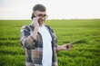 © Serhii - A young farmer inspects the quality of wheat sprouts in the field. The concept of agriculture.