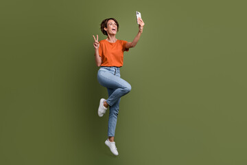 Wall Mural - Full size photo of friendly woman dressed t-shirt in glasses show v-sign make selfie on smartphone isolated on khaki color background