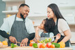 © chokniti - Kind African american parents teaching their adorable daughter how to cook healthy food, free space of kitchen, Happy black people family preparing healthy food in kitchen together