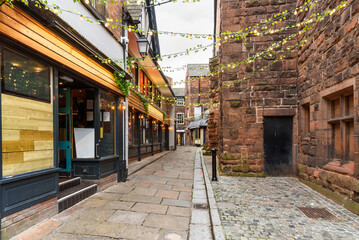 Wall Mural - Deserted cobblestone alley lined with old stone buidings on one side and restaurants on the other side in a historic central district