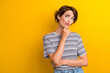 Portrait of suspicious girl with short hairdo wear grey t-shirt hold finger on chin look empty space isolated on yellow color background