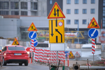 Wall Mural - Roadworks warning traffic signs of construction work on city street and slowly moving cars