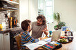 © Marko Geber - Father Helping Son with Homework in a Home Kitchen