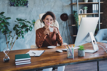 Poster - Portrait of cheerful lawyer lady sitting chair hold fresh morning coffee mug loft interior workplace indoors