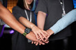 © Seventyfour - Close up of multiethnic female team stacking hands and celebrating victory on stage during competitive eSports event