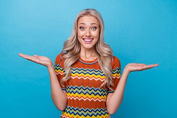 Poster - Photo of excited funky girl dressed print shirt comparing two arms empty space isolated blue color background