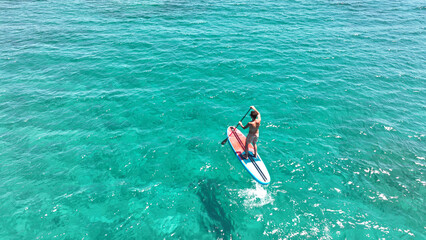 Wall Mural - Aerial drone photo of fit man practise SUP or Stand Up Paddle board in tropical exotic bay with emerald calm sea