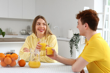 Canvas Print - Young couple drinking orange juice in kitchen