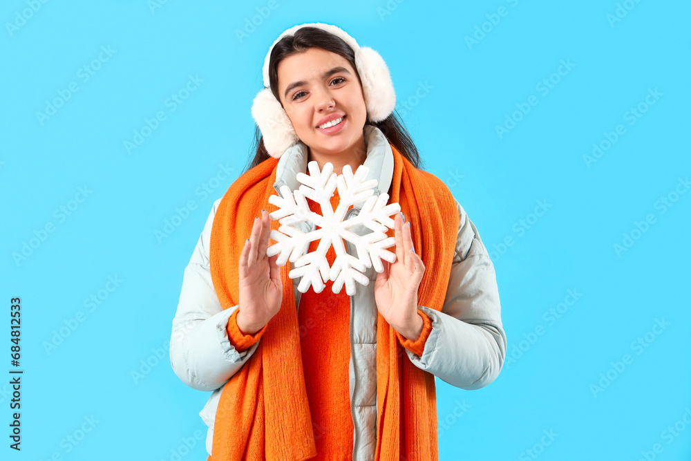Young woman in winter clothes with snowflake on blue background
