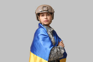 Wall Mural - Young female soldier in uniform with flag of Ukraine on grey background