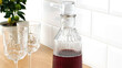 Closeup of wine glass carafe with stopper and glasses on table.
