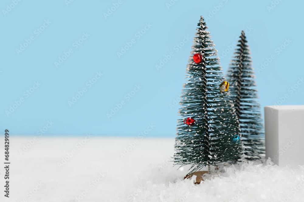 Decorative podium with Christmas trees on snow against blue background