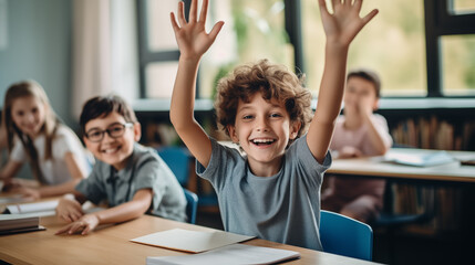 Male pupil in classroom raising his hands and enjoying class