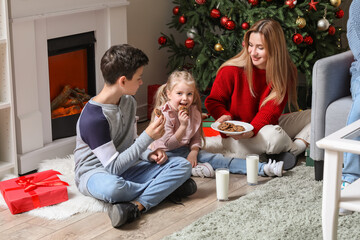 Wall Mural - Little children with their mother eating Christmas cookies at home