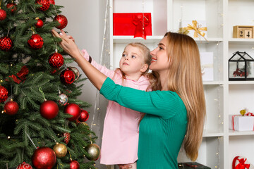 Sticker - Little girl with her mother near Christmas tree at home