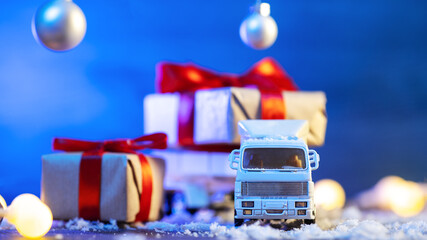 Canvas Print - Toy truck carrying Christmas gifts, blue background, snow and garlands