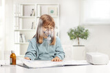 Fototapeta  - Little girl reading a book and using a nebulizer