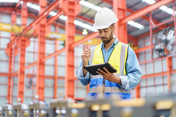 Professional Asian industrial engineer inspecting a heavy machine in metal sheet manufacturing factory.