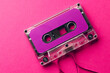 Overhead view of purple cassette tape on pink background