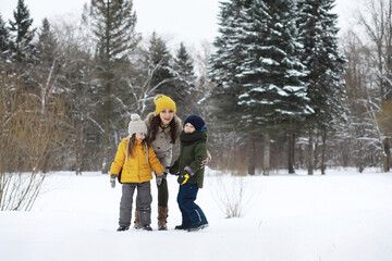 Wall Mural - Happy family playing and laughing in winter outdoors in the snow. City park winter day.