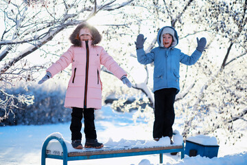 Wall Mural - Family with children play snowy winter games in the park. Winter holidays and family vacation. Winter walk on the street on a sunny frosty day.